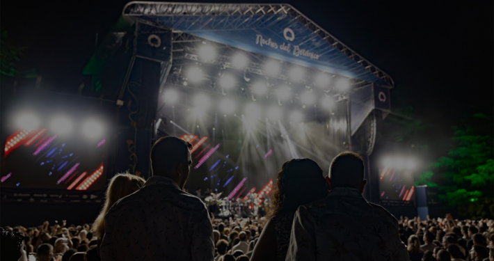 Escenario iluminado con gente disfrutando del concierto